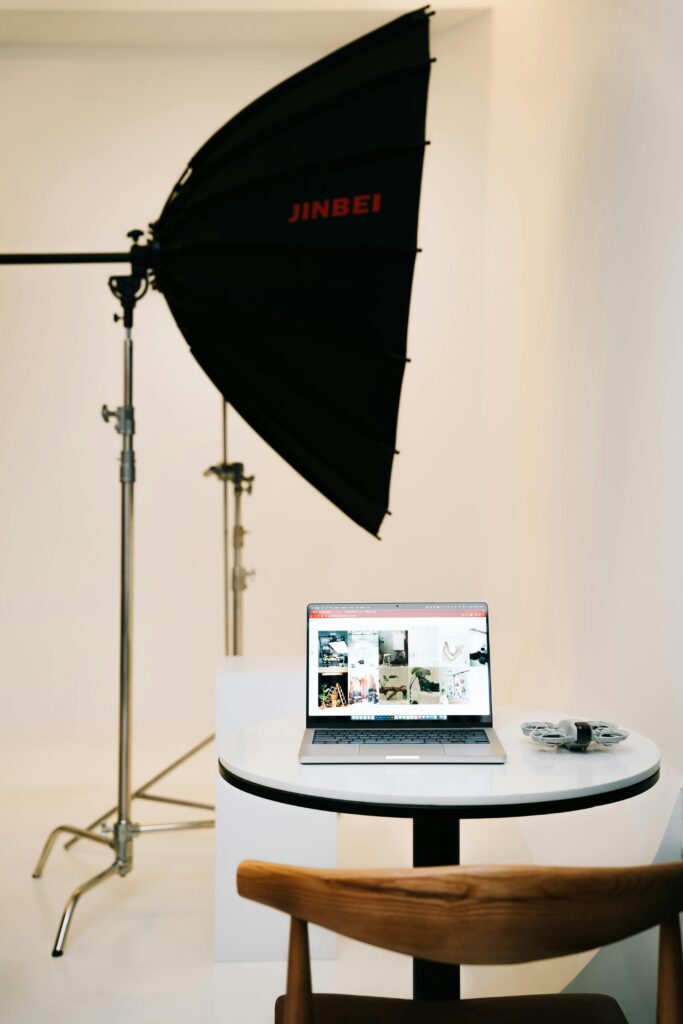 pexels-photo-28772546-28772546 Studio setup featuring a softbox light and a laptop for photo editing, creating a clean and professional workspace.